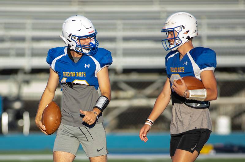 Quarterback Tyler O'Connor, left, talks to quarterback Max Howser during practice at Wheaton North on Thursday, Aug. 11, 2022.