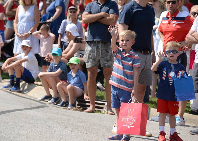 Jack Gajewski (left) of Hinsdale and Leis Threle of Chicago wave to firemen and police officers during the Hinsdale 4th of July parade Tuesday June 4, 2023.
