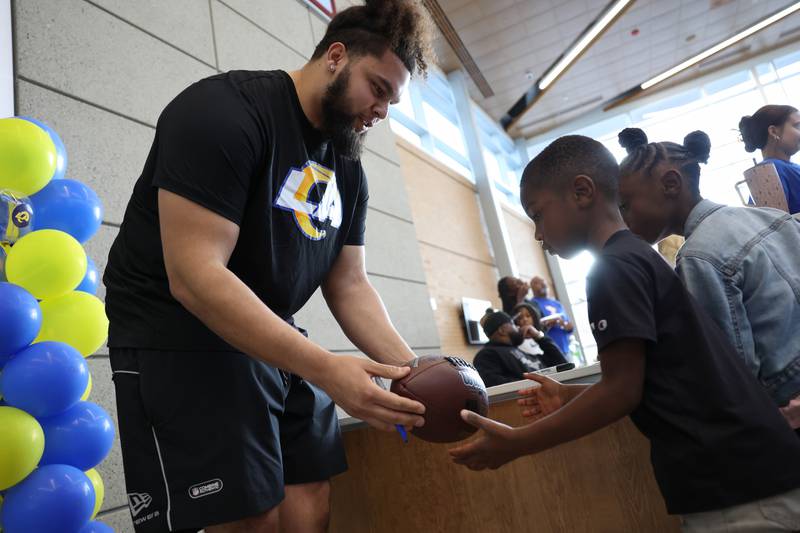 Keagen Trost, a 2019 Kankakee High School grad, sign the football of 5-year-old Khyrie, of Kankakee, during a celebration held for him at the school on May 4, 2026, following him being drafted into the NFL to the Los Angeles Rams.