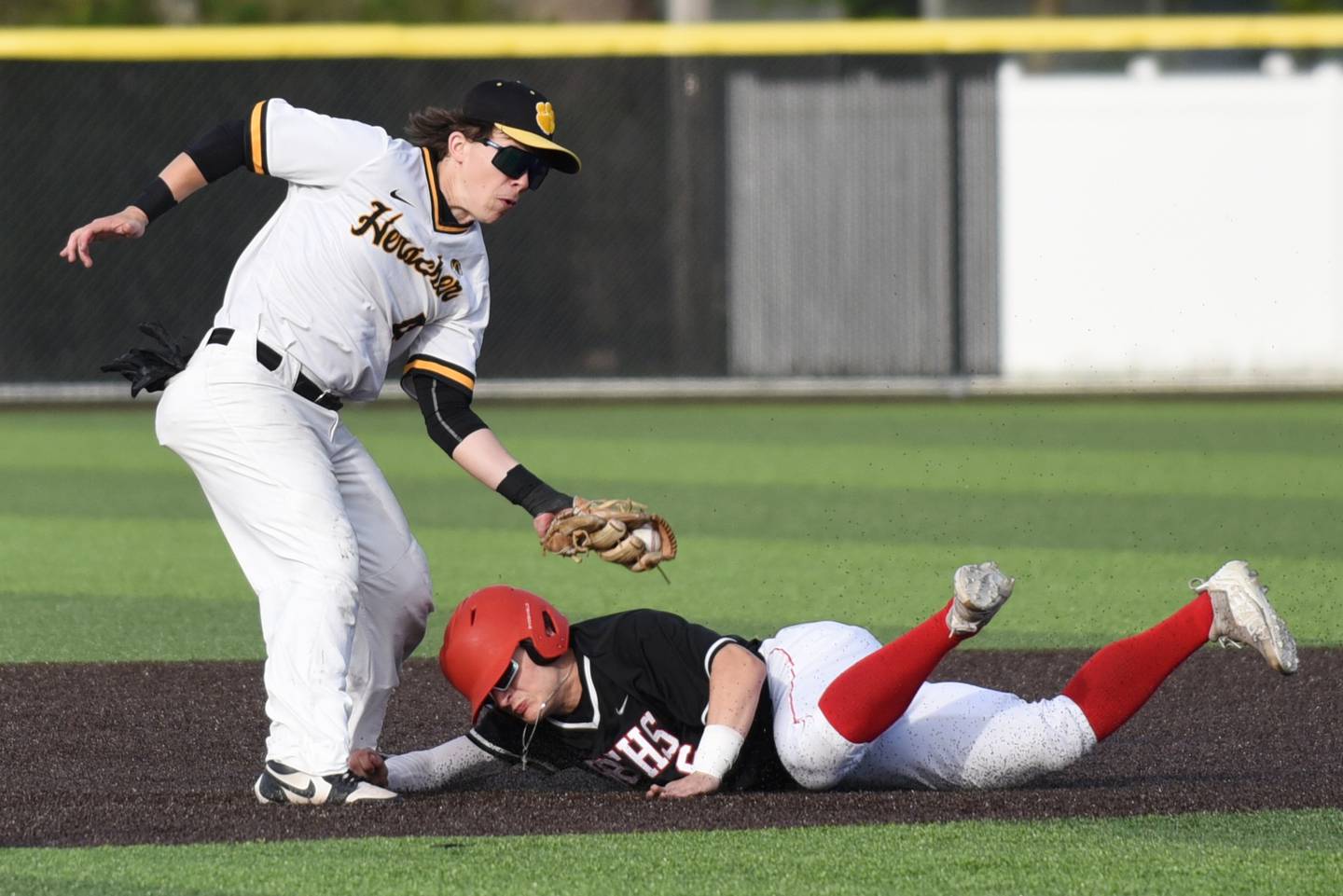 Herscher's Brock Berns, left, applies a tag on Clark Six to catch Six stealing second base during a game at Herscher Friday, April 24, 2026.