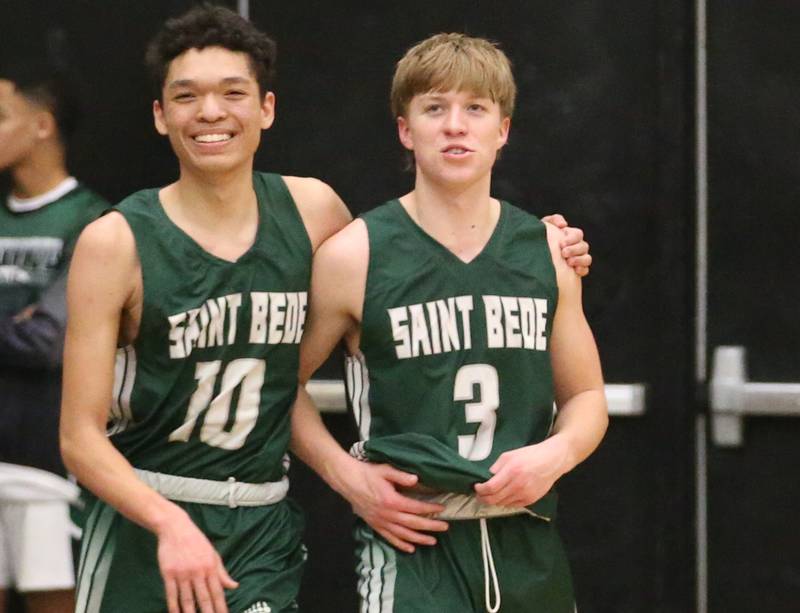 St. Bede's Isiah Hart smiles with teammate Callan Hueneburg as they walk off the court after defeating Marquette in the Class 1A Regional semifinal on Wednesday, Feb. 22, 2023 at Midland High School.