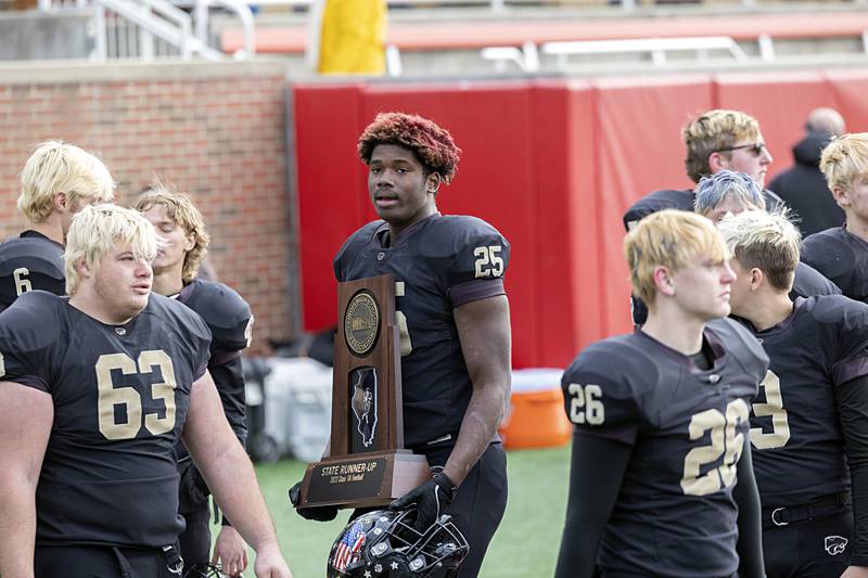 Lena-Winslow's O'Marion Pasley carries the second place trophy after their contest against Camp Point Friday, Nov. 24, 2023 in the 1A state football championship game at Hancock Stadium in Normal.