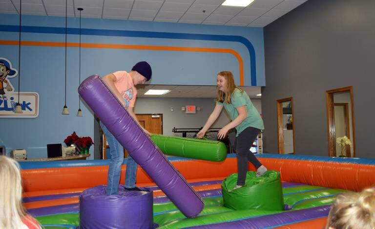 Channing Sarver, 12, of Dixon, left, and Emily Kitson, 13, of Polo, "battle" in an attempt to knock each other off their respective platforms at the Crossroads Community Church's Winter Carnival on Dec. 3, 2022. The carnival was part of the fourth annual Polo Christmas Festival.