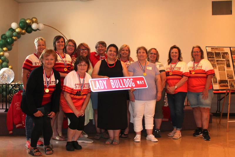 Streator mayor Tara Bedei (at center in front row) holds the "Lady Bulldog Way" street sign that will be installed near the Streator High School softball diamonds at the Night of Champions event Saturday, June 10, 2023, at the Streator PNA Hall marking the 40th anniversary of the Streator softball's state championship. Pictured are (left to right): in front - Zami (Mogill) Hay, RayAnn (Simpson) Weiss, Mayor Bedei, Lori (Dorsam) Drendel, Brenda (Simpson) Gardner and Gina (Wahl) Dresbach; and in back - Linda Weiss, Amy (Pedelty) Ferko, LuAnn (Kozak) Wagner, Lynn (Yanello) Yoerk, Peggy (Killian) Heinz, Julie (Weiss) Gabehart and Marcia (Eccleston) Scudder.