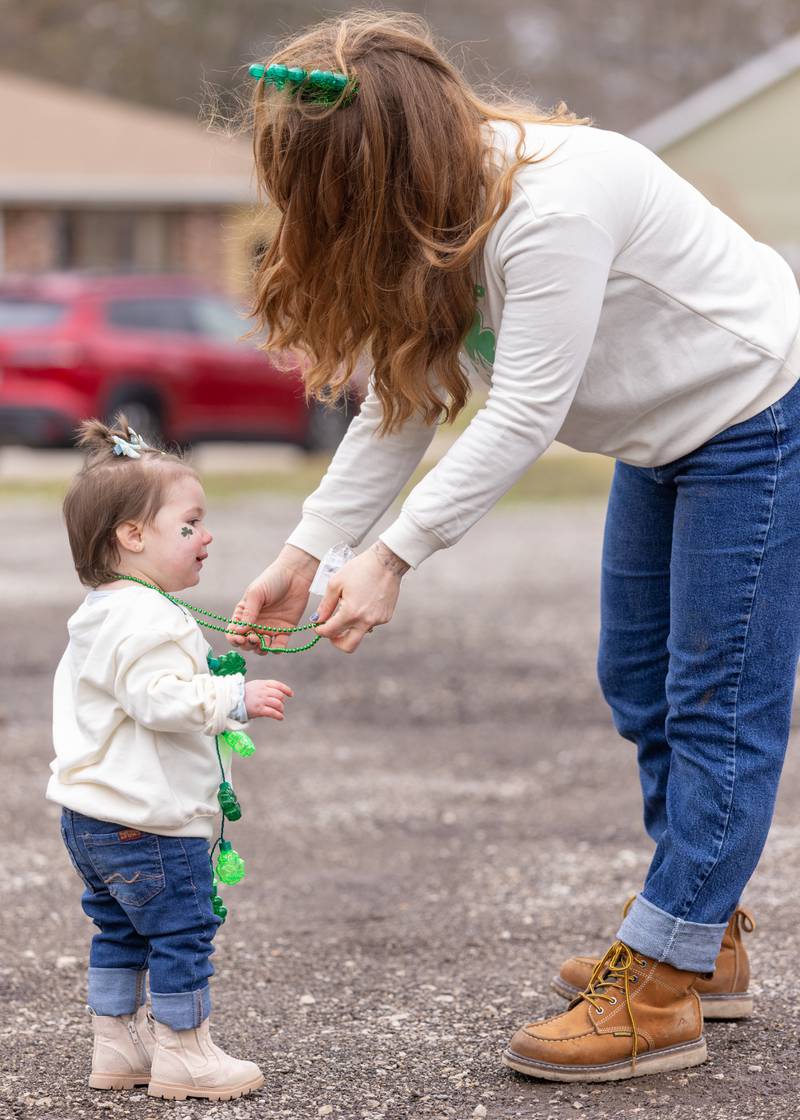 Carly Mendoza places a beaded necklace on her daughter during the St. Patrick's Day Parade on March 7, 2026 in Utica.