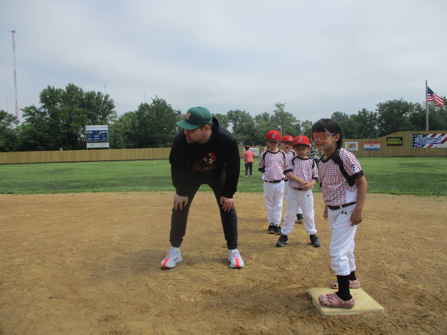 Tommy Gaffney, an account executive with the Slammers, gives base-to-base running instruction to Gabriella Ulloa, age 6, and other Belmont Little Leaguers at their Joliet ballpark. June 14, 2025