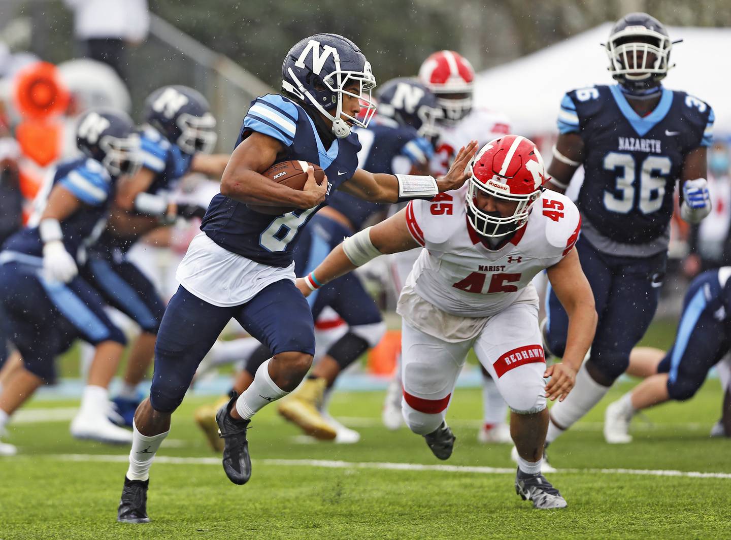 Nazareth's Tyler Morris (8) tries to elude Marist's Triston Schultz (45) as the Marist RedHawk faced the Nazareth Academy Roadrunners on Saturday, April 10, 2021 at Valenta Stadium in La Grange Park, IL. Marist won 13-0.