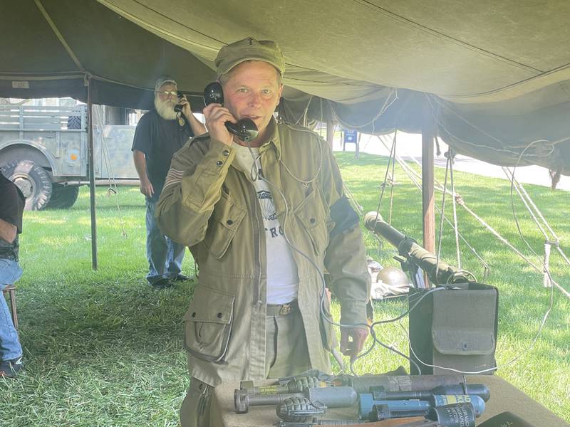Tim Cook (center) is seen picking up a phone call in a living history military encampment set up Saturday, Aug. 2, 2025, during Veterans Weekend outside the Genoa Veterans Home in Genoa.