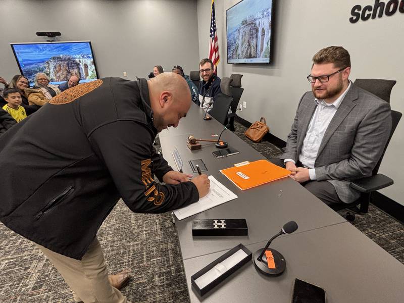 Billy Hueramo signs his new employment agreement at a Jan. 5, 2026, meeting of the DeKalb School District 428 Board of Education.