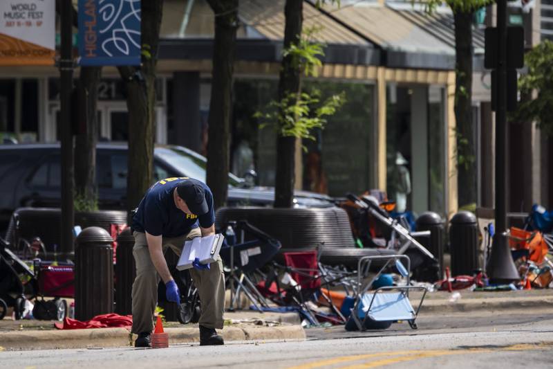 Members of the FBI's Evidence Response Team Unit investigate in downtown Highland Park, Ill., the day after a deadly mass shooting on Tuesday, July 5, 2022.   Police say the gunman who attacked an Independence Day parade in suburban Chicago fired more than 70 rounds with an AR-15-style gun.   (Ashlee Rezin /Chicago Sun-Times via AP)