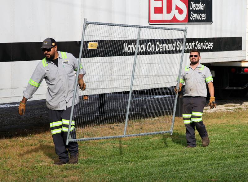 Contractors carry fencing that was being installed around the perimeter of the grounds of the  Joliet Local Training Area site for the Illinois National Guard at 20612 Arsenal Road in Elwood on Tuesday, Oct. 7, 2025.