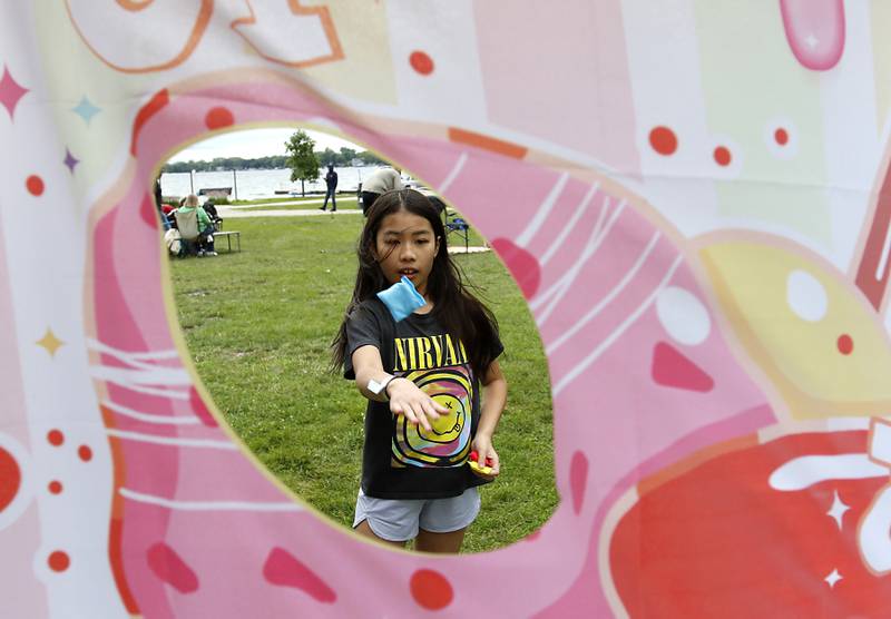 Harper Nguyen, 9, tosses a bag into the Warps Corps bag toss game during the Ice Cream Fest on Friday, Aug. 9, 2024, at Crystal Lake’s Main Beach.  The second annual event featured music, ice cream venders and an ice cream eating contest.