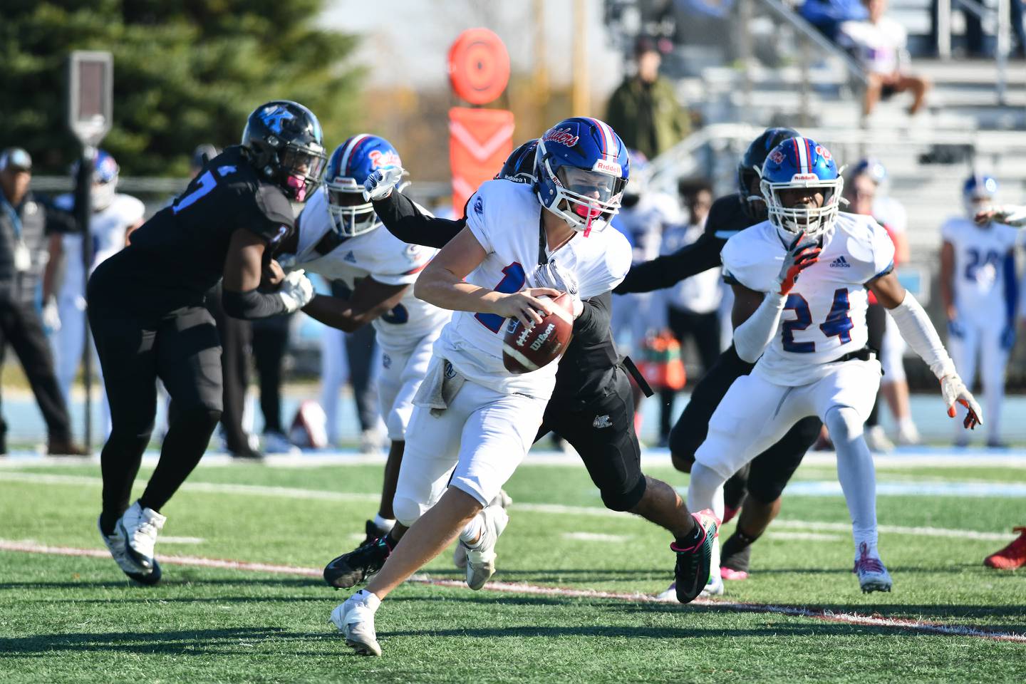 Glenbard South quarterback Tommy Bauman scrambles away from Kankakee's Kennyan Chandler on Saturday during the Raiders' 42-0 loss to Kankakee in the first round of the IHSA Class 6A playoffs.