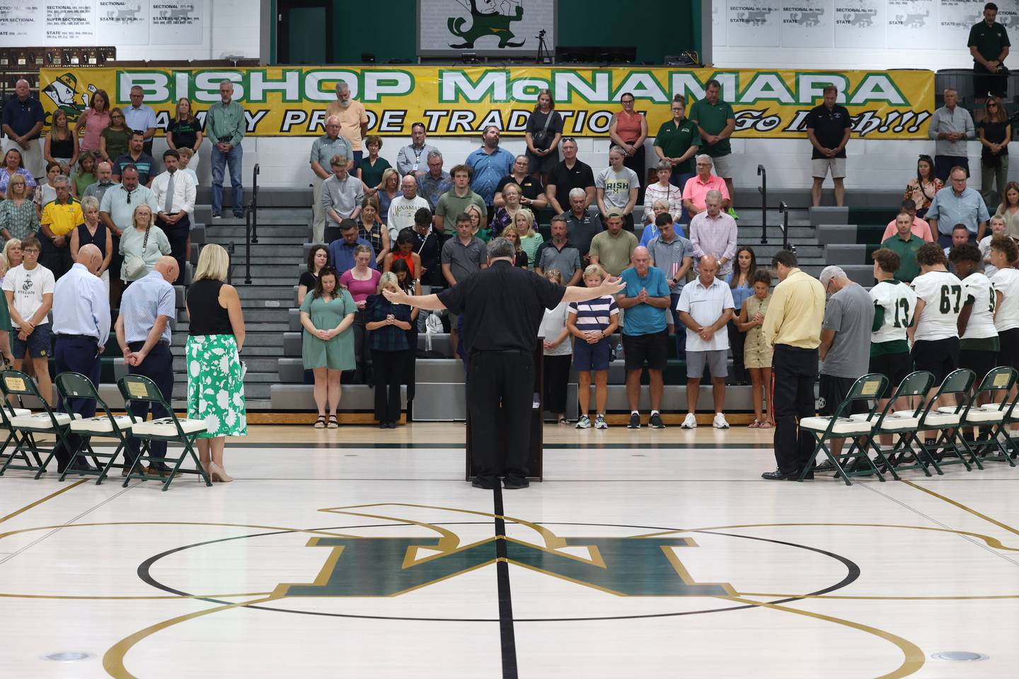 Alumni, students and attendees bow their heads as Fr. Jason Nesbit leads in prayer ahead of Bishop McNamara's ribbon-cutting ceremony for the new Rich Zinanni Athletic Complex on Thursday, Aug. 21, 2025.