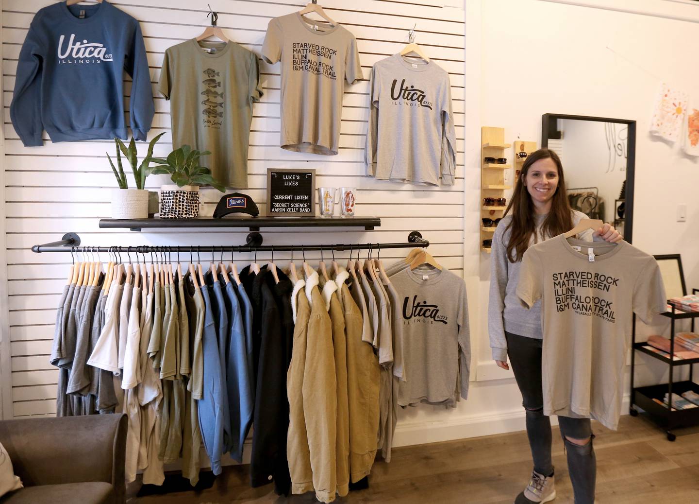 Kylie Mattioda owner of Wears Well holds a Starved Rock and Matthiessen shirt in her store on Monday, Dec. 19, 2022 in Utica.