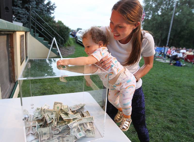 Courtney Zabrin, of Palatine holds her daughter, Nora, sixteen-months-old, as she puts a donation into the box in front of the stage during the final concert of the "It’s Thursday” summer concert series featuring the cover band, Mike & Joe, on August 10th in Antioch. The event and its proceeds were dedicated to Huntley, a child who was injured during the Taste of Summer in July. 
Photo by Candace H. Johnson for Shaw Local News Network