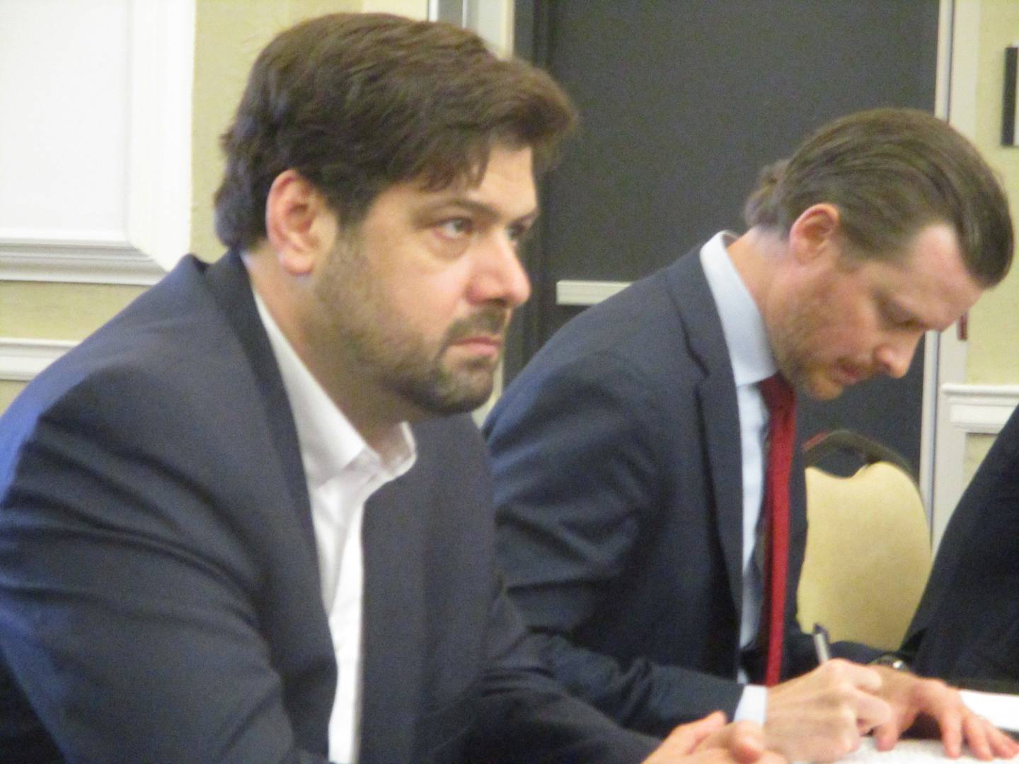 Rob Kalbouss, director of development for Earthrise Energy, (left) and Ben Jacobi, an attorney representing the company, listen to comments made during a public hearing Tuesday on the company's plan to build a 6,100-acre solar complex in Will County. March 31, 2026