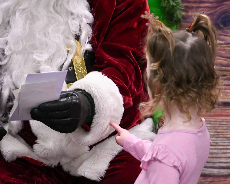 Clodagh Shields, 2, of La Grange feels the fabric of Santa’s jacket as she waits patiently to talk with Santa as her sister Caoimhe goes over her Christmas list on Sunday Dec. 15, 2024, held at the La Grange Park District Recreation Center.