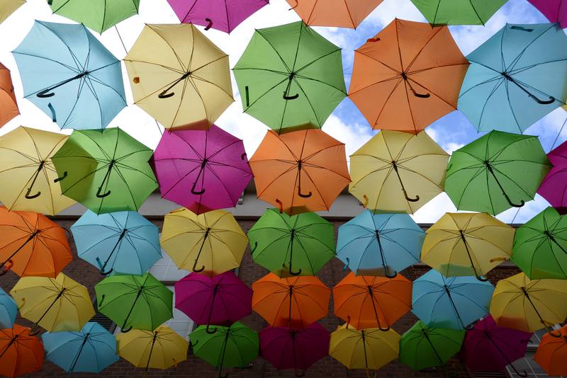 Colorful umbrellas overhang Schiller Court during the Public Art Commission's Umbrella Sky Project Opening Day Party held Saturday April 29, 2023.
