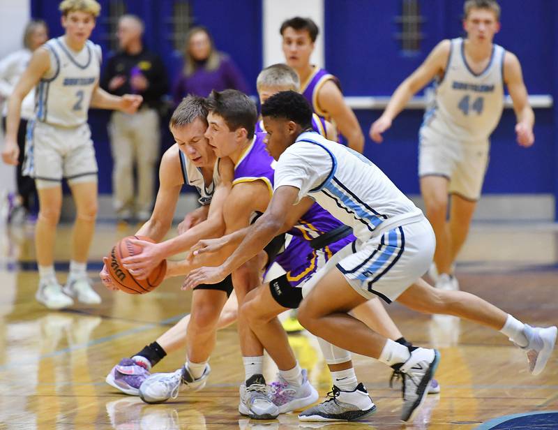 Downers Grove South's Daniel Sveiteris (left) and Jalen House squeeze Downers Grove North's Jack Stanton as they battle for a loose ball during a crosstown game on Dec. 17, 2022 at Downers Grove South High School in Downers Grove .