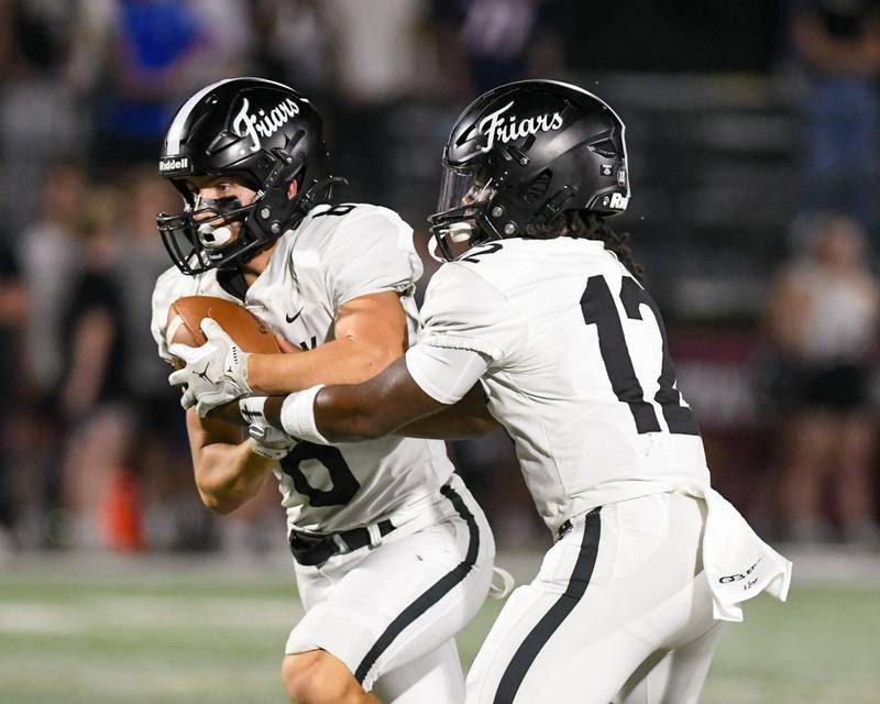 Fenwick's Jamen Williams, right, hands the ball off to teammate Jake Thies (8) during the game on Friday Sept. 19, 2025, while traveling to take on Montini Catholic's High School.