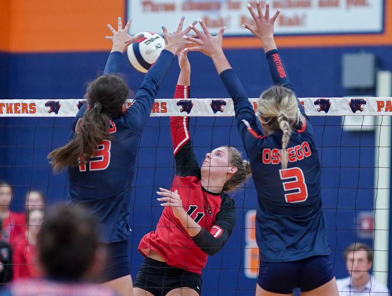 Yorkville's Clare Knoll (11) goes up for a kill against Oswego’s Sidney Hamaker (13) and Riley Borrowman (3) during a volleyball match at Oswego High School on Thursday, Sept. 14, 2023.