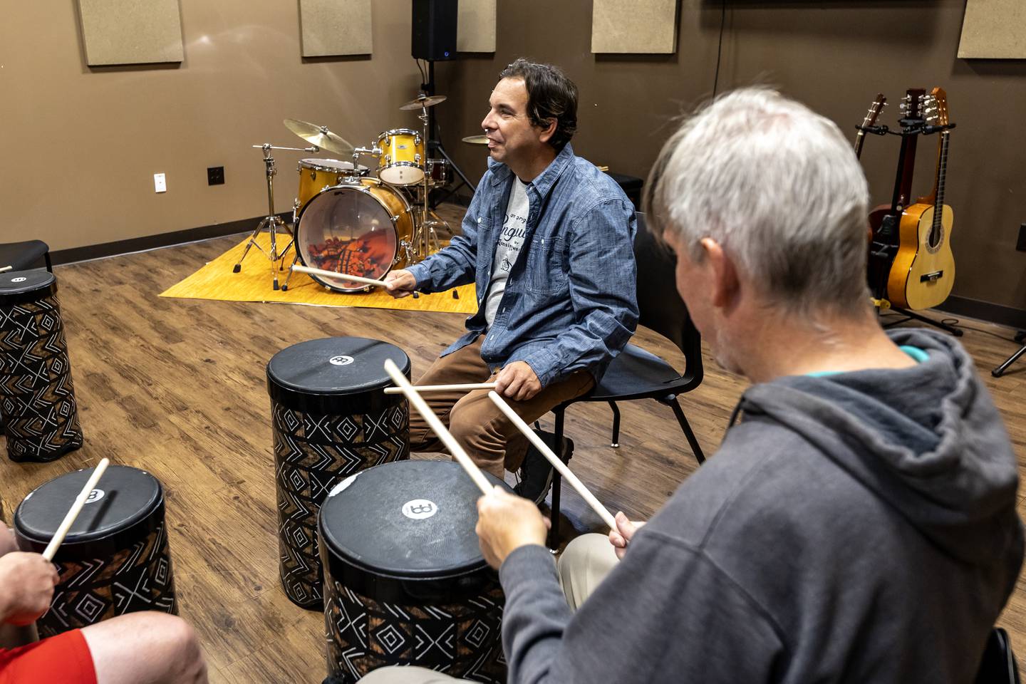 Craig Schulz, a direct support professional with Trinity Services, leads a drum group at Studio 22 in New Lenox on Aug. 28, 2025.