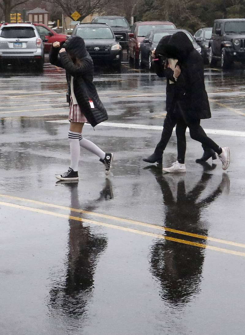 People cover their heads from the weather as they walk into the McHenry County courthouse in Woodstock on Wednesday, Feb. 22, 2023, as a winter storm that produced rain, sleet, freezing rain, and ice moved through McHenry County.