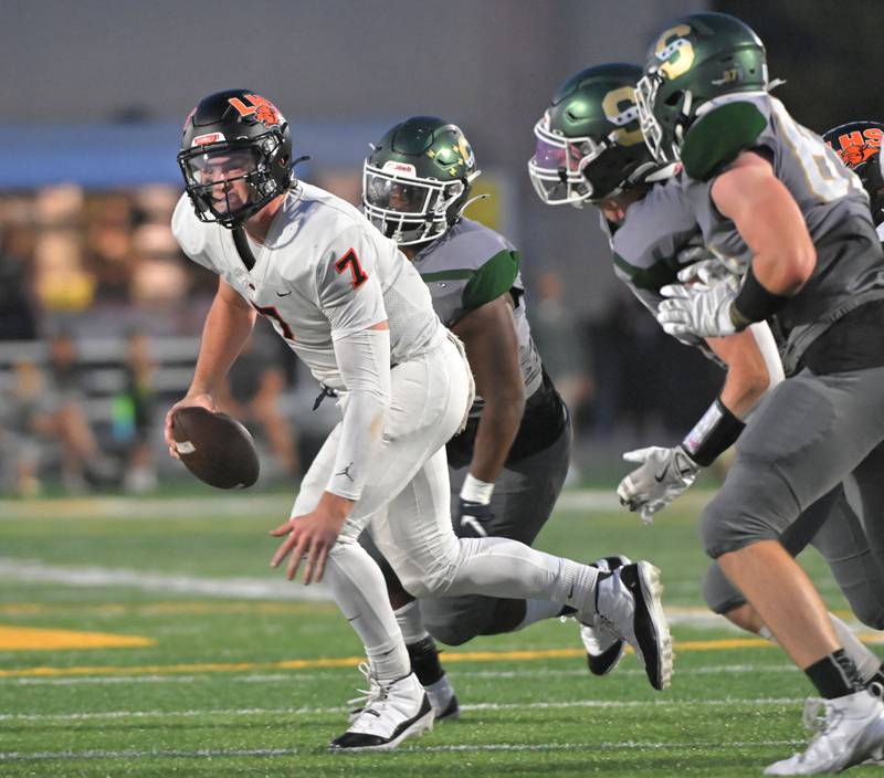 Libertyville quarterback Quinn Schambow is chased by the Stevenson defense before throwing a touchdown pass to Sam Seth in a football game in Lincolnshire on Friday, Sept. 13, 2024.