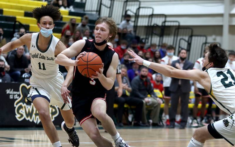 Huntley’s Nathan Ary, center, brings the ball to the hoop past Crystal Lake South’s Isaiah Kirkeeng, left, and Cooper LePage, right, in boys varsity basketball at Crystal Lake South Friday night.