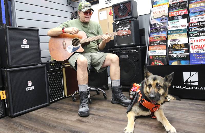 U.S. Marine Corps veteran Marshall Boyle, from DeKalb, plays guitar with his German Shepherd service dog, Lucy, Friday, Sept. 22, 2023, at Aurora Music Company in DeKalb. Boyle serves as an ambassador to Guitars 4 Vets and volunteers for Habitat for Humanity.