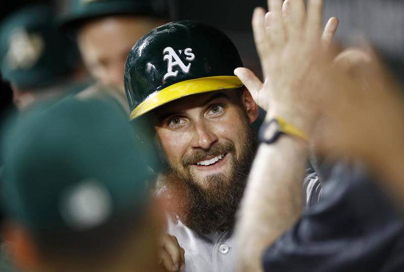 The Oakland Athletics' Nick Martini, a 2008 Prairie Ridge graduate from Crystal Lake, high-fives teammates in the dugout after scoring on Matt Chapman's single against the Baltimore Orioles last season in Baltimore. Martini hit a pinch-hit, two-run homer in the eighth inning of the A's 6-5 loss to the Cubs on Monday night at Wrigley Field.