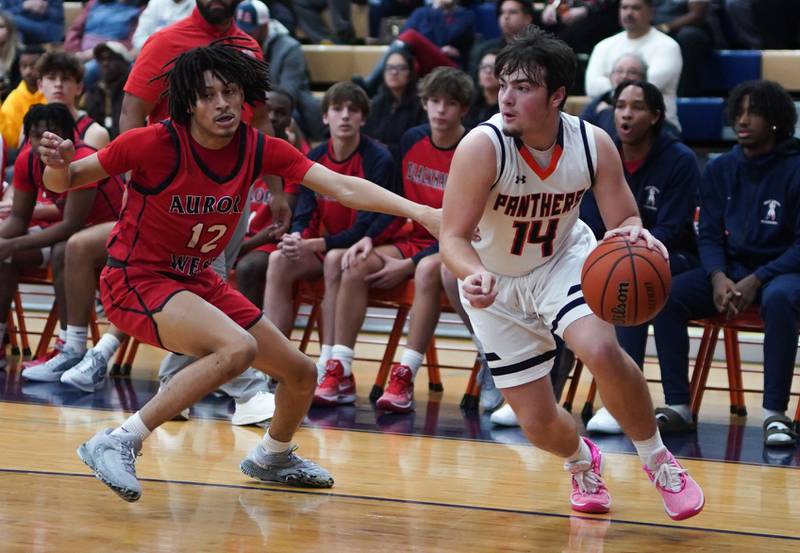 Oswego’s Brogan Mello (14) plays the ball on the baseline against West Aurora's Mike Evans (12) during a basketball game at Oswego High School on Friday, Dec 1, 2023.