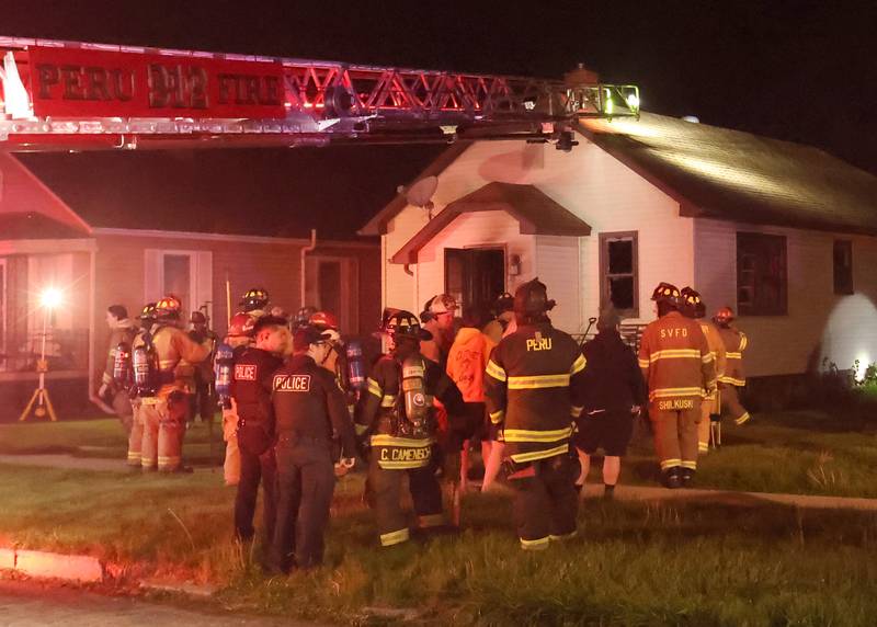 Firefighters gather around a home in the 500 block of West Erie street for a structure fire on Monday, May 4, 2026 in Spring Valley. The fire happened shortly before 10:45p.m. A Mutual Aid Box Alarm System (MABAS) call was dispatched for additional fire departments from Eastern Bureau County, Peru, Utica, Oglesby and La Salle.