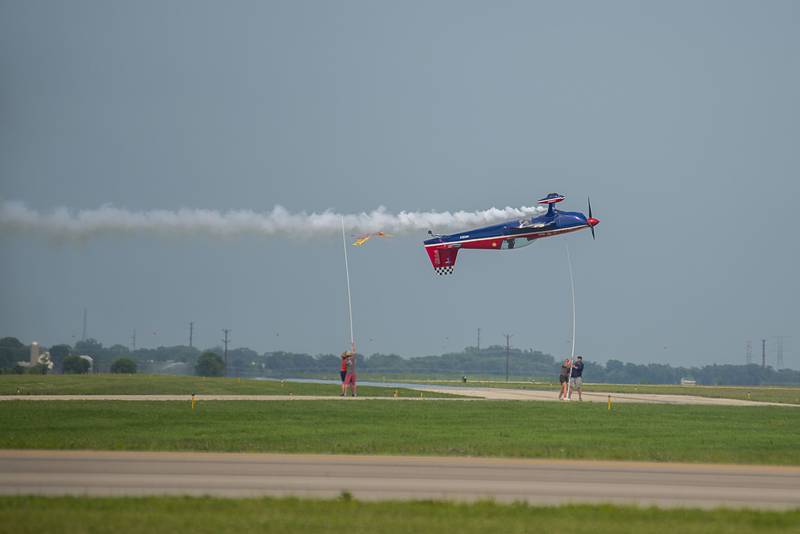 Flying upside down, stunt flier Patty Wagstaff cuts a ribbon mere feet off the ground to end her performance Saturday, July 23, 2022 during the airshow.