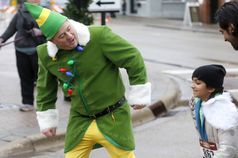 Chris Christensen, dressed as Buddy the Elf, challenges Amaliya Parikh to a race to the finish line during the McHenry County Santa Run For Kids on Sunday morning, Dec. 3, 2023, in Downtown Crystal Lake. The annual event raises money for agencies in our county who work with children in need.