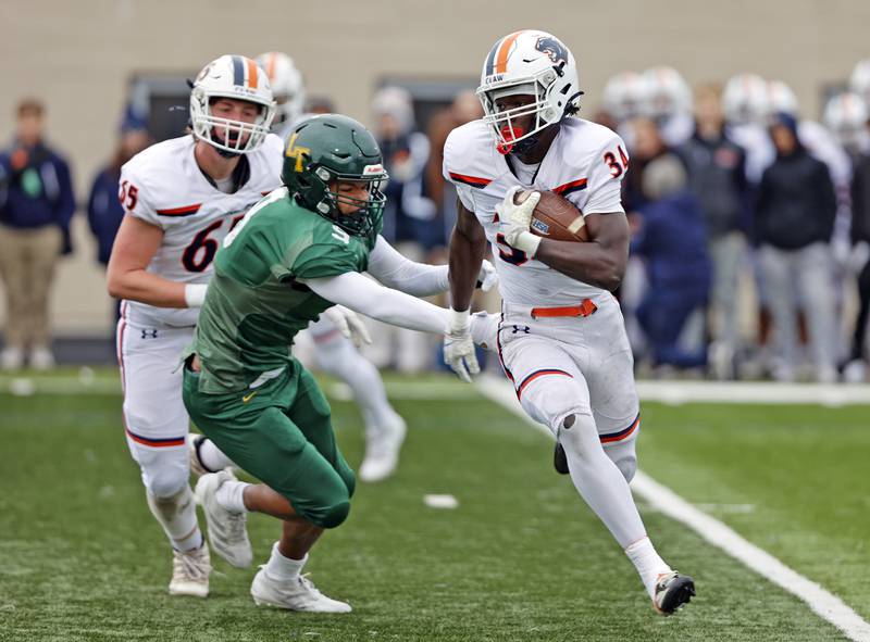 Oswego's Ammar Banire (34) runs with the ball during the varsity football second-round 8A playoff game between Oswego and Lane Tech on Saturday, Nov. 8, 2025 in Chicago.