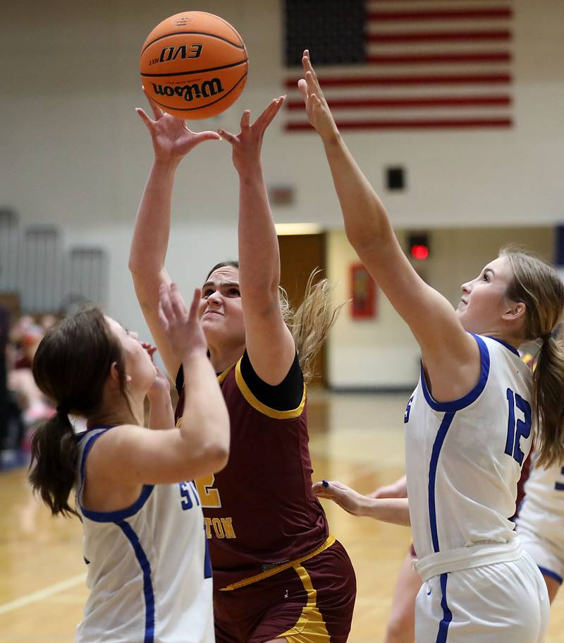 Richmond-Burton's Matilda Furzland (center) grabs a rebound between Woodstock's Emma Douglas (left) and Hayden Williams (right)during a Kishwaukee River Conference girls basketball game on Wednesday, Jan. 28, 2026, at Woodstock High School.