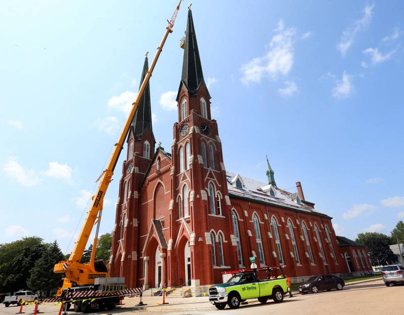 Workers use a large crane to shingle the two spires at St. Hyacinth Church on Thursday, July 25, 2024 in La Salle.