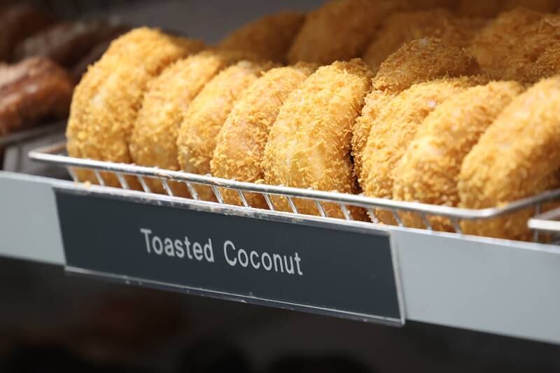 Freshly glazed cake donuts hang on a rack at Home Cut Donuts on Jefferson Street, Saturday, March 25, 2023 in Joliet.