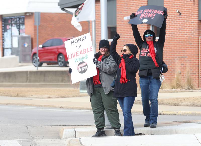 Sue O'Brien, Deb Vancleve, and Taylor Stacy hold signs that read "honk for livable wage$" and "Fair Contract Now" during a “Fight Like Hell” rally held by the National Association of Letter Carriers on Sunday, Feb. 22, 2026 at the United States Post Office in Peru.