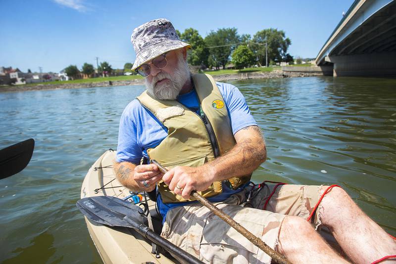 Mark Stach looks over the jagged edge of a piece of metal he pulled up while fishing with a magnet on Tuesday in the Rock River.
