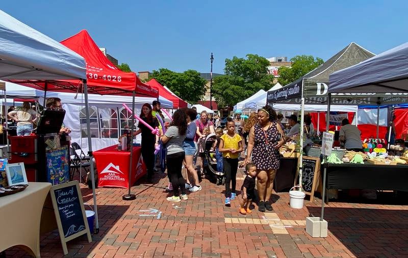 Families browse vendor stands during the opening day of the DeKalb farmers market on Thursday, June 5, 2025, in Van Buer Plaza in downtown DeKalb. The market opened its 30th year Thursday.