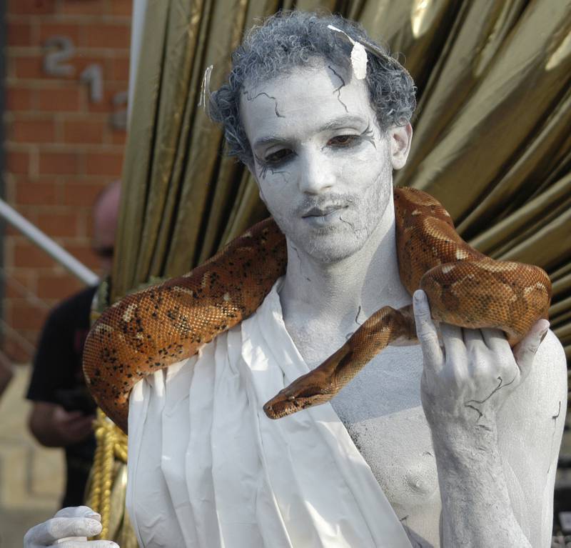 Performer Xavier Barnhand of Dixon Stage Left stands like a statue with a snake Saturday,  Aug. 9, 2025, at Venetian Night in Dixon. The event, hosted by Discover Dixon, featured magicians, street performers, face painting, a spaghetti eating contest, mini boat races, and a drone light show.
