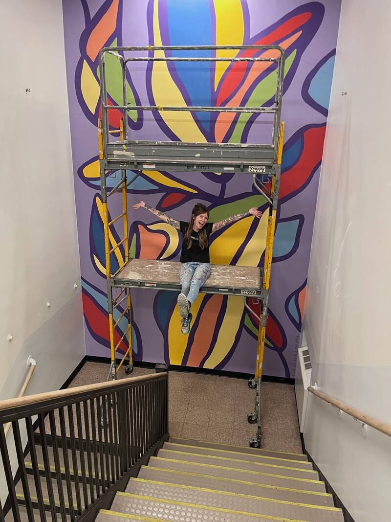 Sara Jean Stevens next to one of her murals she created in a stairwell at Husmann Elementary School in Crystal Lake.