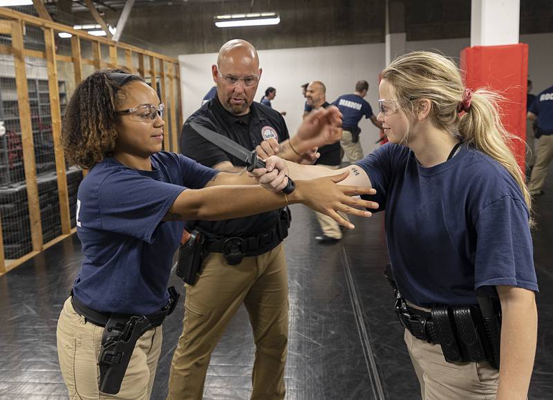 John Atkins instructs recruits Marielys Sanchez (left) and Paige Talty on knife defense Wednesday, July 17, 2024, at the Sauk Valle Police Academy.