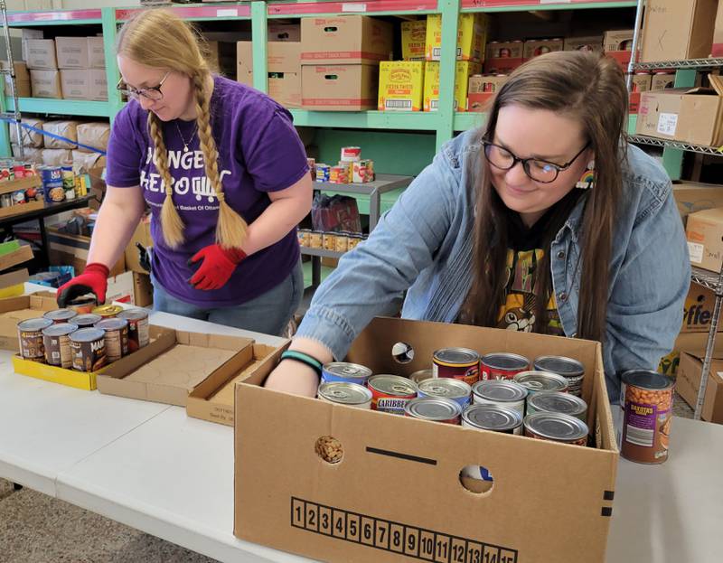 Community Food Basket of Ottawa executive director Marissa Vicich (right) and staffer Madeline Orr pack up some canned goods for the move to shelves in the pantry's store.