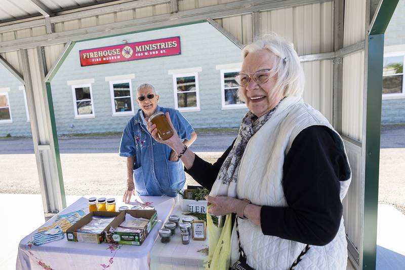 Nancy Lauritzen picks up a jar of homemade jelly made by Pam Drane (left) Wednesday, May 1, 2024 at the Rock Falls Farmers Market.