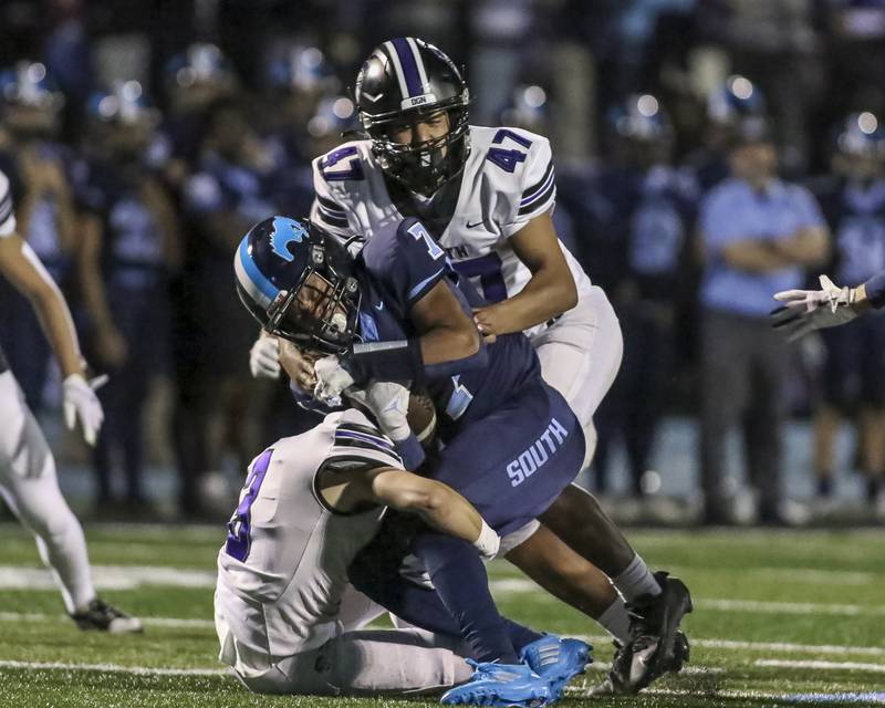 Downers Grove South's Antoine Hardin (7) is tackled by Downers Grove North's Philip Moawad (47) and Jonathan Nelson (3) during football game between Downers Grove North at Downers Grove South Friday, Sept 5, 2025  in Downers Grove.