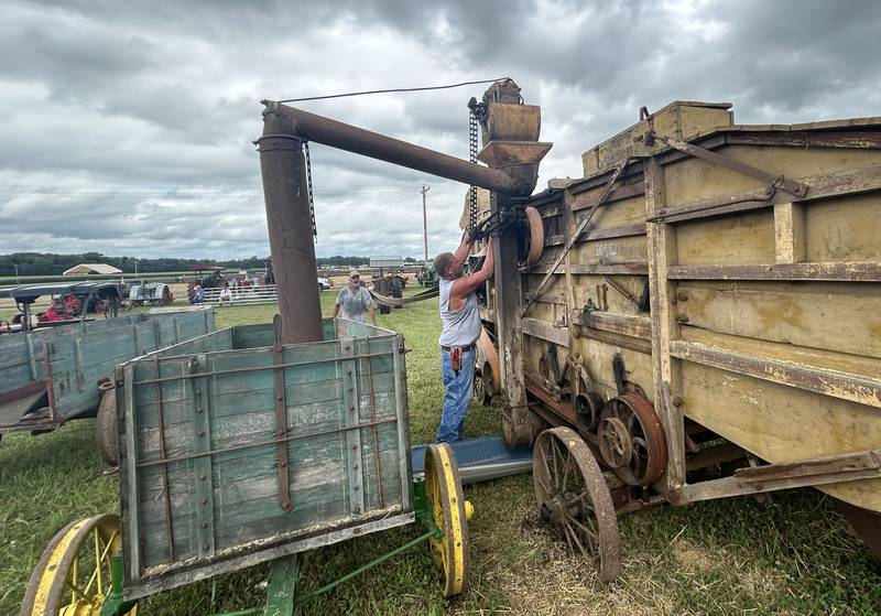 A volunteer reaches to adjust a belt and pulley on a threshing machine at the Bos Brothers Historical Farm south of Erie on Saturday, July 26, 2025. This year's event focused on harvesting wheat.